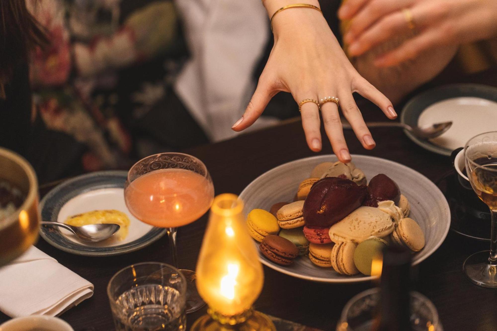 Hotel Pigalle Göteborg Exteriér fotografie A woman's hand reaches for a plate of macarons